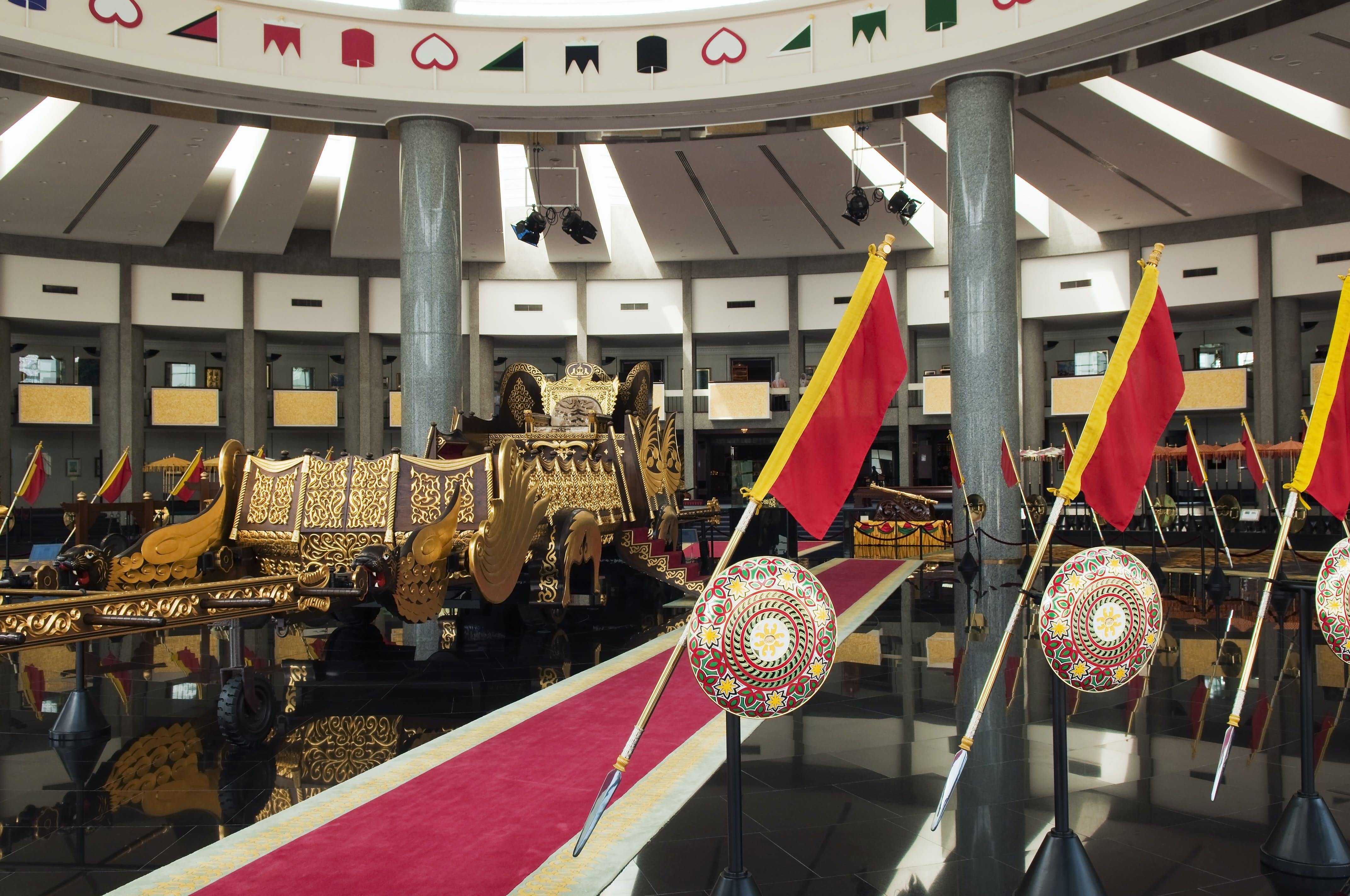 Interior of ther Royal Regalia Museum with sultan's gilded coronation cart and shields.