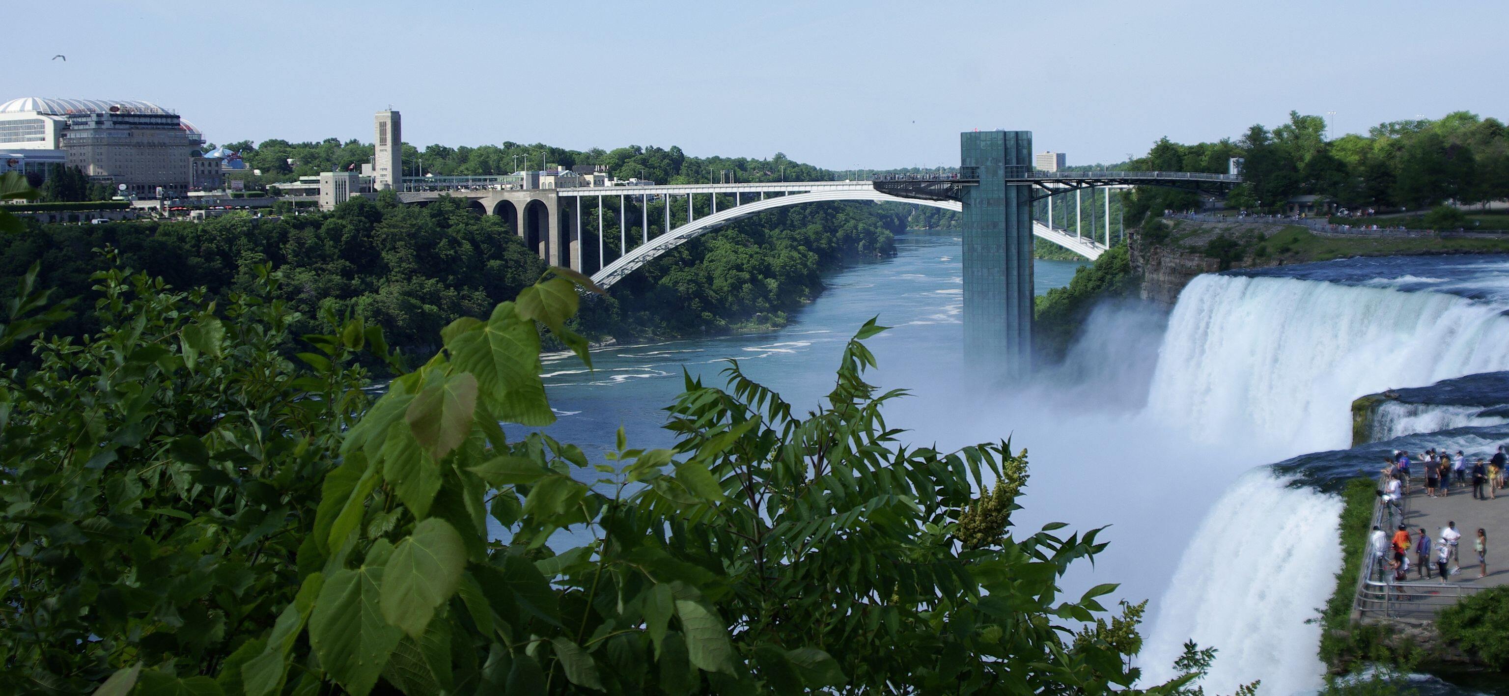 A photograph of the Rainbow Bridge and the Prospect Point Observation Tower. The American Falls lie in the foreground. The photograph was taken on Luna Island.